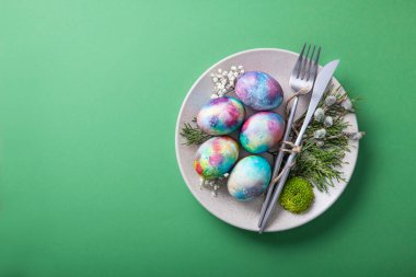 Plakalı Paskalya minimalizmi yemek kavramı ve yeşil arka planda boyanmış yumurtalar. Üst Manzara. kopyalama alanı.