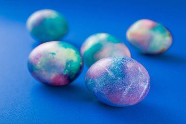 Mavi arka planda renkli yumurtalarla mutlu Paskalyalar.