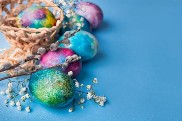 Mavi arka planda bahar çiçekleri olan mistik renkli yumurtalar. Paskalya tatili konsepti.