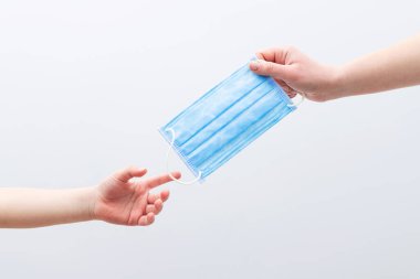 Beyaz bir arka planda elinde tıbbi maske tutan bir doktor. Coronavirus koruma kavramı.