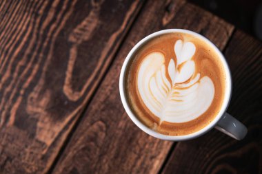 Ahşap bir masada bir fincan kapuçino köpüğü. en üstteki görünüm