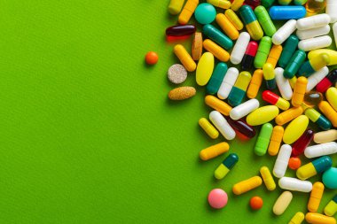 Çok renkli haplar ve kapsüller, yeşil arka planda vitaminler. Üst Manzara. Metin için yer.