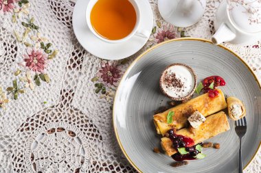 Tereyağlı, reçelli, ekşi kremalı krep, eski masa örtüsü üzerinde sıcak çay bulunan nane yaprakları. Üst Manzara. Çay töreni..