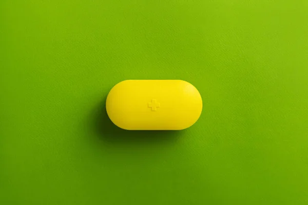 Pojemnik Żółtymi Pigułkami Zielonym Tle Widok Góry Koncepcja Leczenia — Zdjęcie stockowe