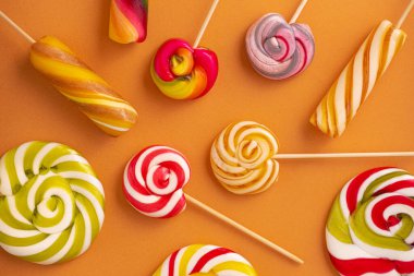 Turuncu arka planda renkli lolipoplar. Yaz şekerleri konsepti.
