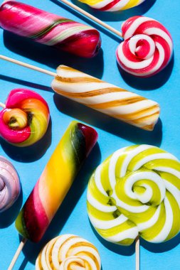 Mavi arka planda renkli lolipoplar. Yaz ve pop sanat konsepti. Üst görünüm.