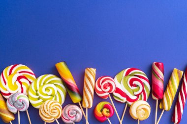 Lolipop renkli bir arka planda şekerleme mırıldanıyor. Trend yiyecek minimum konsept. Düz Yat. Üst görünüm.