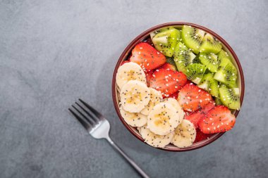 Taş bir masada taze meyve salatası, Chia ve susam tohumları. Sağlıklı beslenme geçmişi. Üst görünüm.