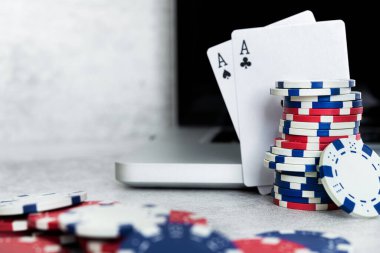 Online poker oyunları, gri arkaplanda dizüstü bilgisayarı olan çipler ve kartlar.