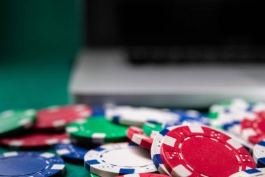 Kumarhane masasında gümüş rengi poker fişleri ve modern dizüstü bilgisayar.. 