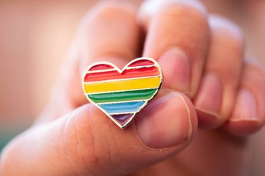 Renkli gökkuşağı şeklinde kalp şeklinde bir simge ellerinde. Sokakta geçit töreni. Makro fotoğraf.