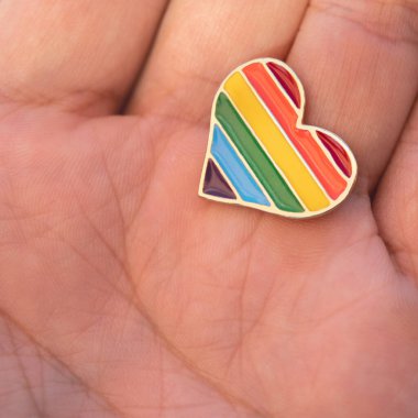 Renkli gökkuşağı şeklinde kalp şeklinde bir simge ellerinde. Sokakta geçit töreni. Makro fotoğraf.