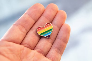 Renkli gökkuşağı şeklinde kalp şeklinde bir simge ellerinde. Sokakta geçit töreni. Makro fotoğraf.
