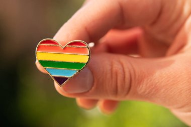 Renkli gökkuşağı şeklinde kalp şeklinde bir simge ellerinde. Sokakta geçit töreni. Makro fotoğraf.