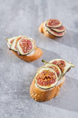 Krem peynirli üç bruschetta ve taze incir, arka planda susam tohumu.. 