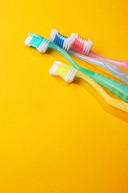 Sarı arka planda dört diş fırçası.