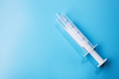 Mavi arka planda enjeksiyon için klasik boş şırınga. en üstteki görünüm.