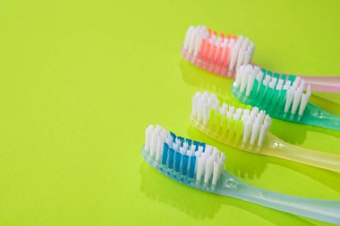 Yeşil arka planda yeni renkli diş fırçaları. Aile diş sağlığı konsepti.