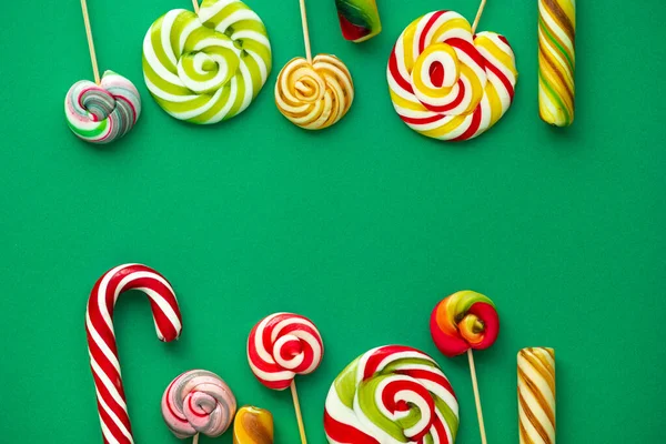 おいしいキャンディは緑の背景に異なる色をLolypops ポップアートの概念 上からの眺め — ストック写真
