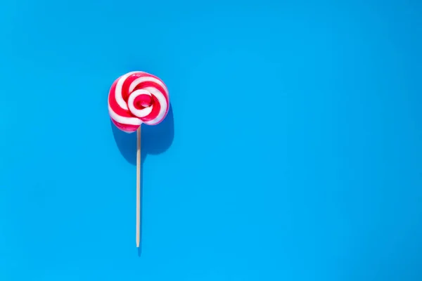 蓝色背景上的一个红色白色棒棒糖夏天和流行艺术的概念 顶部视图 — 图库照片