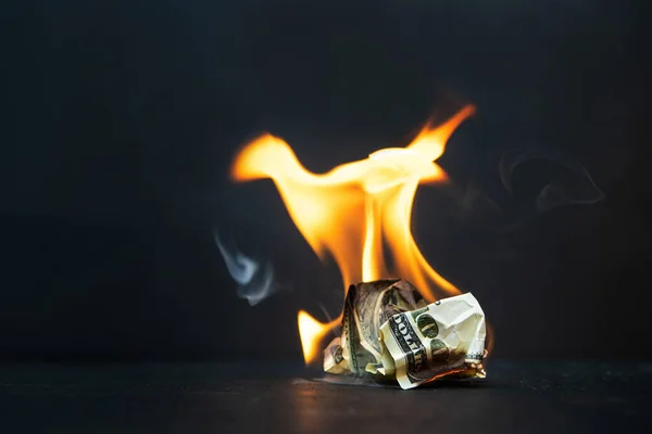 Crumpled dollar bills burning fire on a dark background. Economic crisis and downturn and bankruptcy, shutdown.