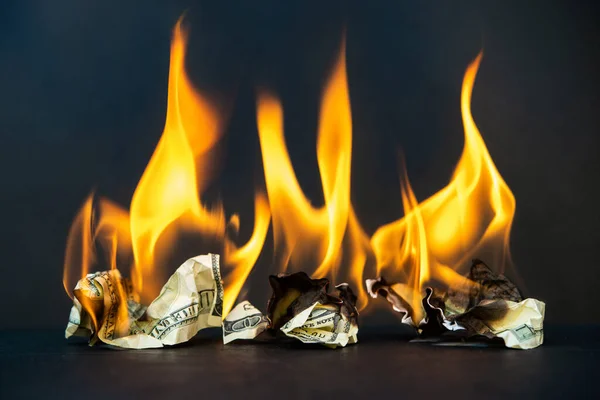 Crumpled dollar bills burning fire on a dark background. Economic crisis and downturn and bankruptcy, shutdown.