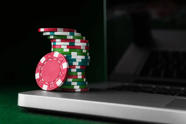 Play online poker with laptop, money colored chips on pc background.