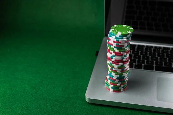 Play online poker with laptop, money colored chips on pc background.