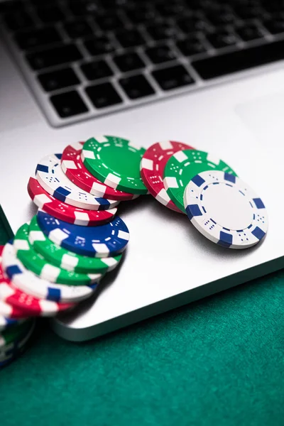 Poker game online with laptop on a green background table. vertical photo
