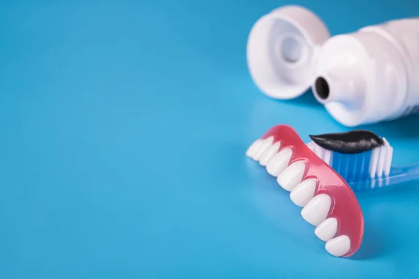 Zwarte Houtskool Tandpasta Een Tandenborstel Model Kaakgebit Blauwe Achtergrond — Stockfoto