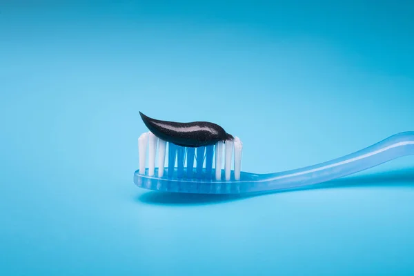 Diş Fırçasında Siyah Kömür Diş Macunu Mavi Arkaplan — Stok fotoğraf