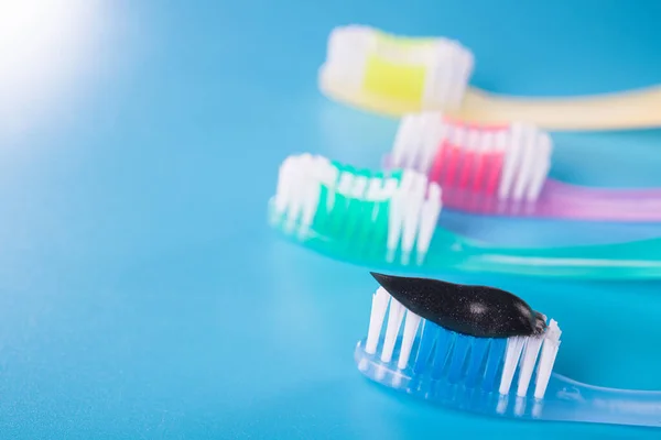 Set Van Vier Kleurrijke Tandenborstels Met Zwarte Houtskoolpasta Een Blauwe — Stockfoto