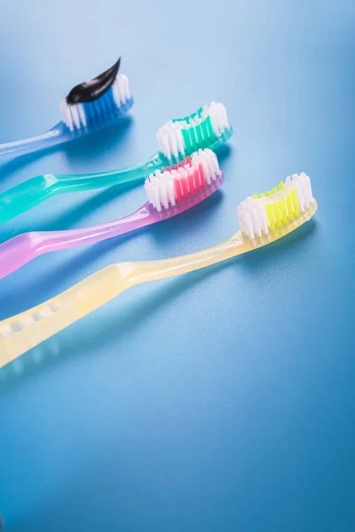 Set Four Colorful Toothbrushes Black Charcoal Paste Blue Background — Stock Photo, Image