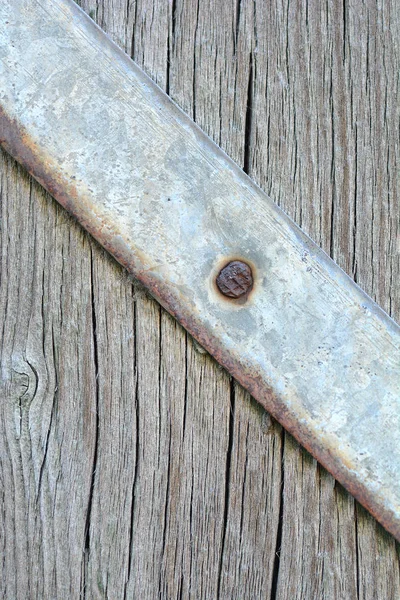 Placa de metal com parafusos sobre o fundo de madeira — Fotografia de Stock