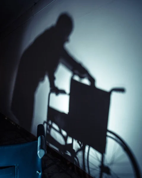 Больные люди и инвалидное кресло, тень на стене — стоковое фото