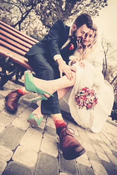 新娘和新郎穿着鲜艳的衣服坐在长椅上 — 图库照片