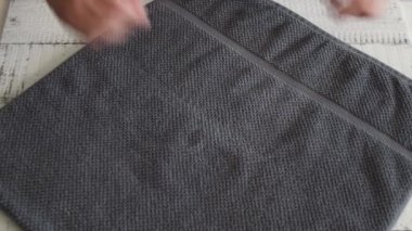 Gri bir havlu katlama Womans rafa yerleştirmek için.