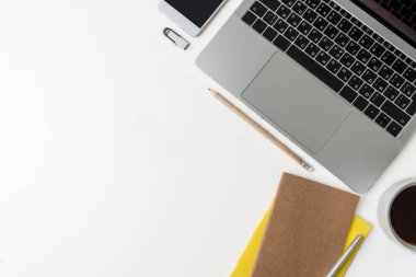 Üstten görünüm office çalışma alanı'nın. Kopya alanı ile beyaz masası. Dizüstü bilgisayar, telefon, dizüstü bilgisayarlar, flash sürücü, fincan kahve, kalem ve kurşun kalem ile tabloda düz yatıyordu görünümü. Yaratıcı tasarımcı kavramı.