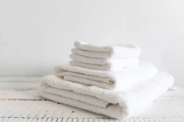 Toalhas de banho brancas dobradas na mesa de madeira branca. Spa e bem-estar, algodão têxtil terry . — Fotografia de Stock
