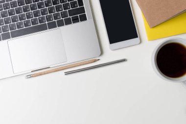 Üstten görünüm office çalışma alanı'nın. Kopya alanı ile beyaz masası. Dizüstü bilgisayar, telefon, dizüstü bilgisayarlar, fincan kahve, kalem ve kalem ile tabloda düz yatıyordu görünümü. Yaratıcı tasarımcı kavramı.