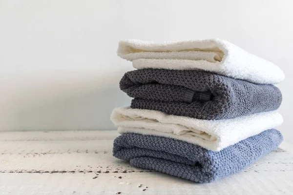 Bir sürü beyaz ahşap masa üzerinde beyaz ve gri banyo havlusu. Spa ve sağlıklı yaşam, pamuk terry Tekstil.