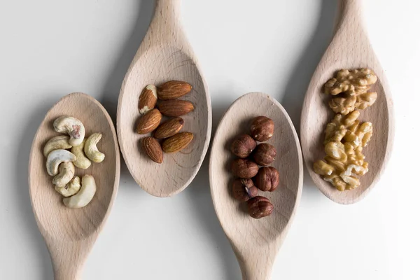 Piles Walnuts Ceshews Almond Hazelnuts Wooden Spoones White Background Nuts — Stock Photo, Image