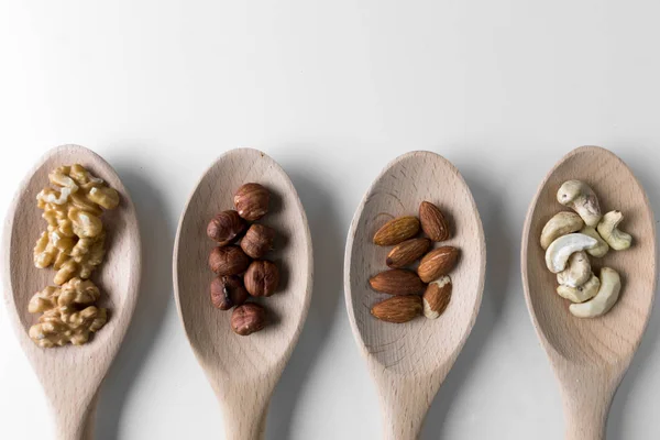 Piles Walnuts Ceshews Almond Hazelnuts Wooden Spoones White Background Nuts — Stock Photo, Image