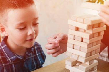 Kadın ve çocuk jenga oyunu oynuyorlar. Tahta bloklar kule dengesini tutmaya çalışıyorum. Aile memnuniyetti zaman. Risk ve stratery iş ve inşaat kavramı.