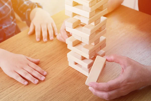 Kadın ve çocuk jenga oyunu oynuyorlar. Tahta bloklar kule dengesini tutmaya çalışıyorum. Aile memnuniyetti zaman. Risk ve stratery iş ve inşaat kavramı.