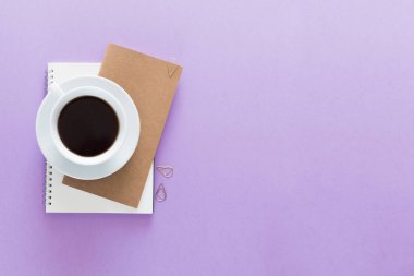 Üstten görünüm defter, kahve ile çalışma masası üzerinde. Metin için yer kopyalayın. Açık mor renkli üzerinde bir çalışma alanı'nın düz lay.