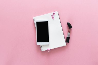 Üstten Görünüm açılan Notebook, ruj ve üstündeki bu telefon ile güzellik çalışma masası üzerinde. Metin için yer kopyalayın. Düz pembe arka plan üzerinde yatıyordu.