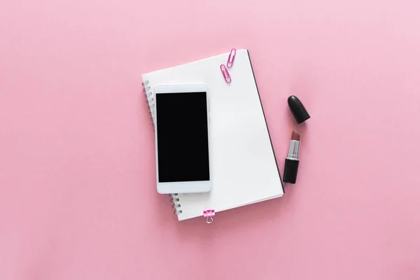 Üstten Görünüm açılan Notebook, ruj ve üstündeki bu telefon ile güzellik çalışma masası üzerinde. Metin için yer kopyalayın. Düz pembe arka plan üzerinde yatıyordu.