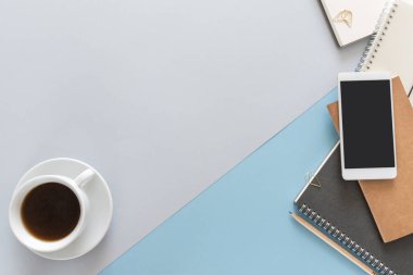 Üstten görünüm dizüstü bilgisayarlar, fincan kahve, kalem, ataç, kalem ve telefon ile çalışma masası üzerinde. Metin için yer kopyalayın. Düz beyaz arka plan üzerinde bir çalışma alanı'nın yatıyordu.