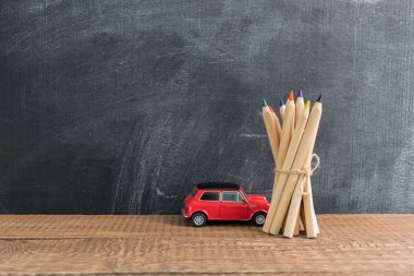 Bir grup küçük kırmızı araba oyuncak yakınındaki bir iple bağlı kalemler üzerinden yan görünüm. Geri okul kavramı